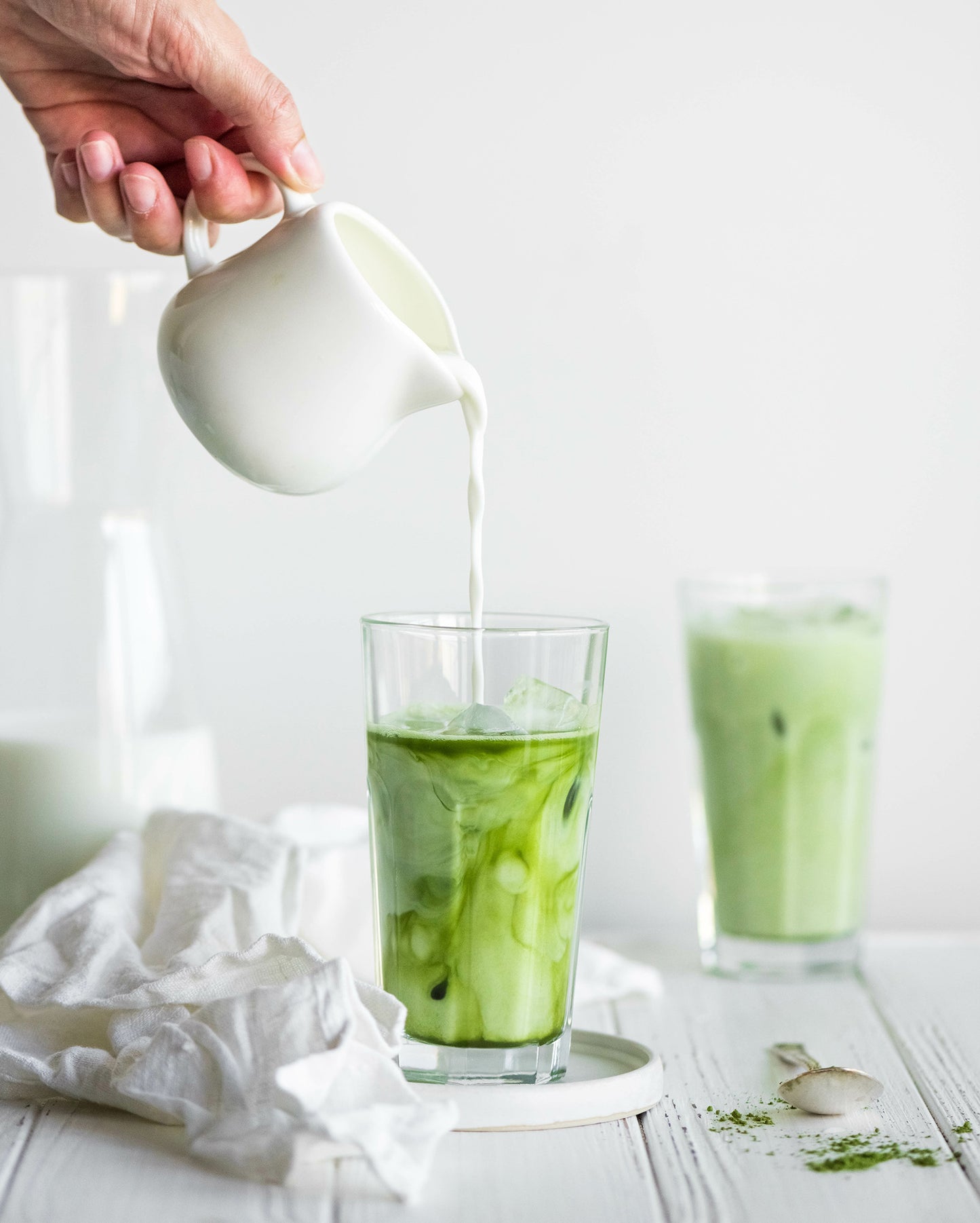
                  
                    Person pours oat milk into glass of iced matcha
                  
                